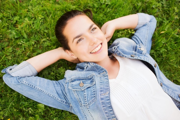 Lifestyle, Sommerurlaub, Freizeit und People-Konzept - lächelndes junges Mädchen in leerem weißem Hemd, das auf Gras liegt