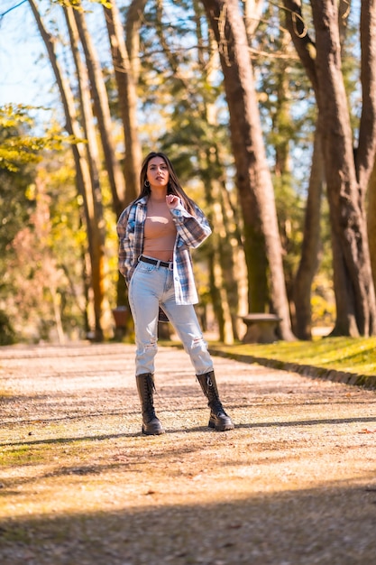 Lifestyle, uma jovem morena caucasiana com um suéter de lã xadrez e jeans rasgados em um parque no outono