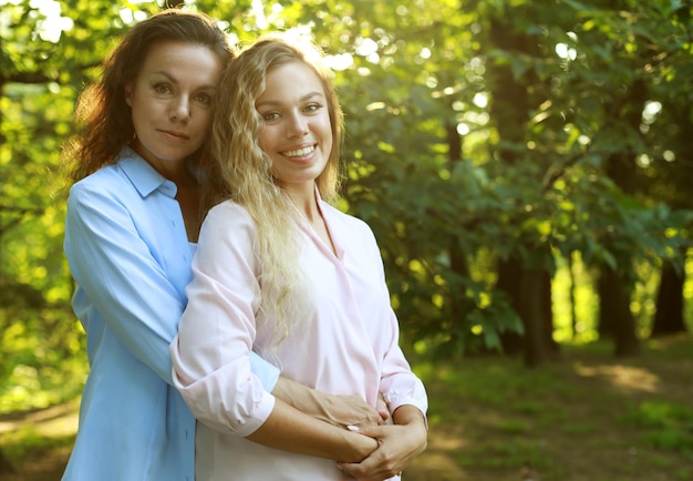 Foto lifestyle- und people-konzept reife mutter und erwachsene tochter umarmen sich an einem sommertag im park