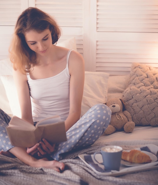 Lifestyle und People-KonzeptMädchen im Bett lesen und Kaffee trinken