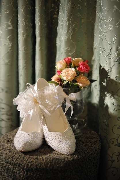 Liga e flores elegantes dos sapatos da noiva em um fundo