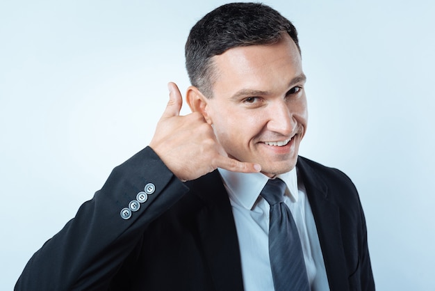 Liga para mim. Homem bonito, alegre e simpático sorrindo e olhando para você enquanto mostra um gesto de chamada com a mão