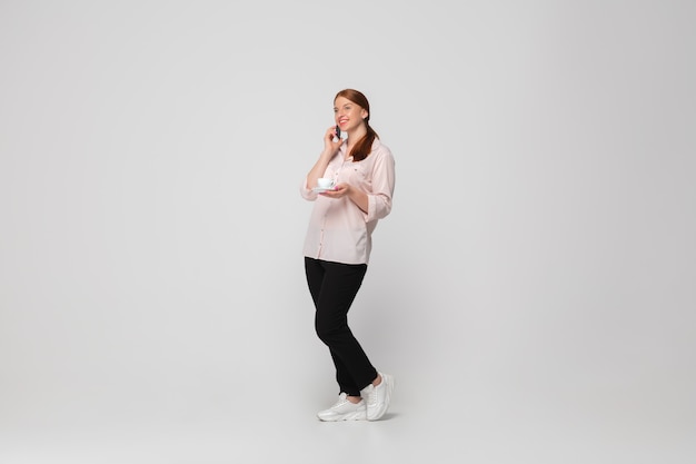 Ligando para o telefone. jovem mulher com roupa desportiva em fundo branco. caráter corpopositivo, feminismo, amar a si mesma, conceito de beleza. plus size empresária durante a papelada. inclusão, diversidade.