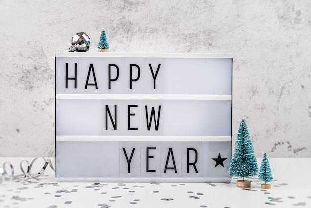 Lightbox carta blanca con feliz año nuevo rodeado de decoraciones navideñas vista frontal