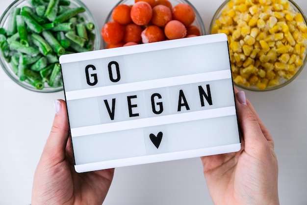 Foto lightbox com texto go vegan três tigelas de legumes congelados comida de milho amarelo feijão verde vermelho