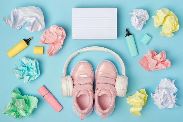 Lightbox em branco Fones de ouvido sapatos cor de rosa marcador de bolas de papel amassado colorido no fundo azul Conceito de educação Flat Lay Vista superior Natureza morta Modelo de modelo