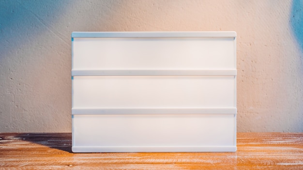 Foto lightbox em branco sob a luz do sol em um suporte de madeira