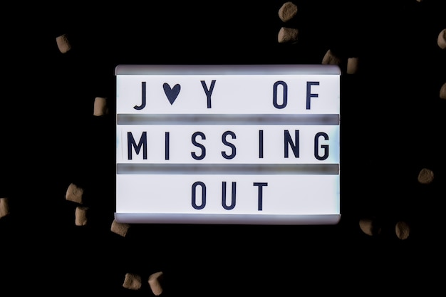 Lightbox mit Text JOMO Joy of Missing Out. Das Konzept der Entspannung von Informationen und Gadgets. Ansicht von oben. Flach liegen. Digitale Entgiftung