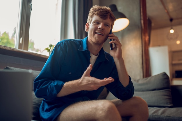 Ligue do trabalho. Um jovem ruivo falando ao telefone e parecendo envolvido