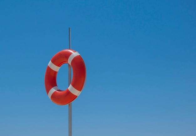 Foto liifebuoy rojo en el polo sobre fondo de cielo azul