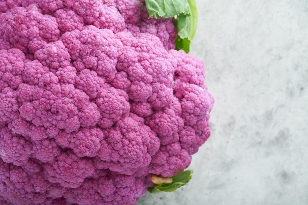 Lila Blumenkohl auf grauem Betongrund Brokkoli und Romanesco