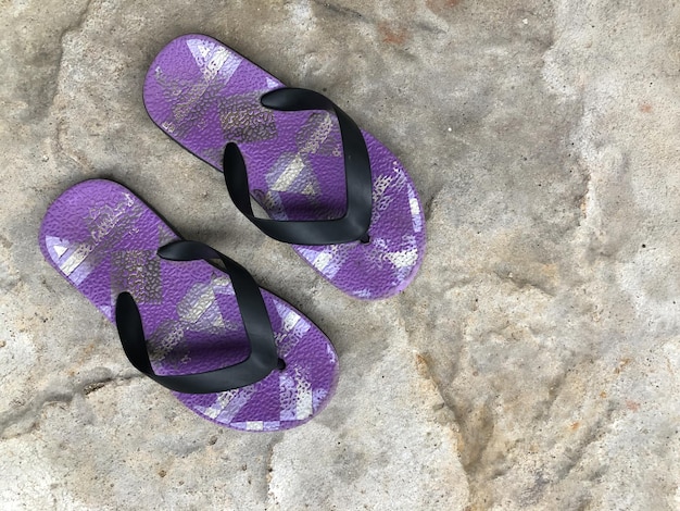 Lila Flip-Flop-Sandalen auf dem Zementboden