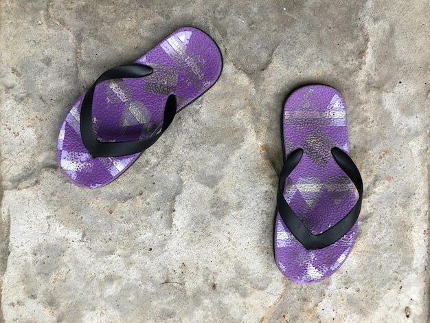 Lila Flip-Flop-Sandalen auf dem Zementboden