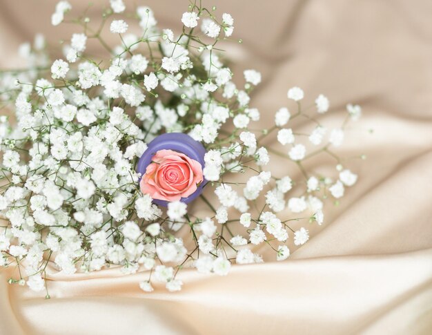 Lila Menstruationstasse mit weißen Blüten und einer Rose im Inneren