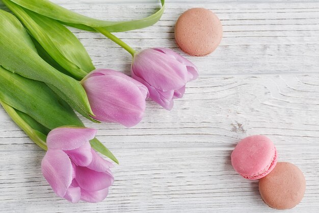 Lila Tulpen und süße pastellfarbene französische Makronen auf Holztisch