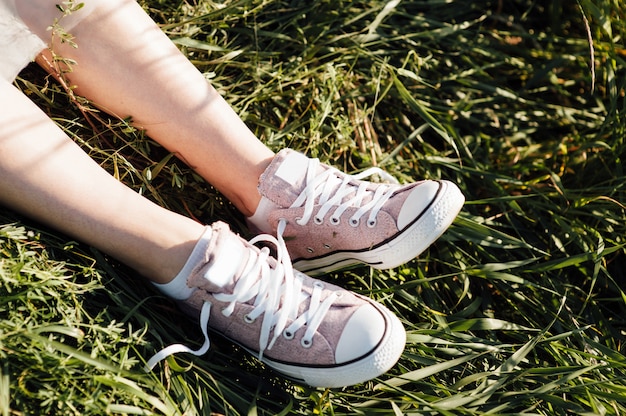 Lila Turnschuhe auf Mädchenbeinen im Gras