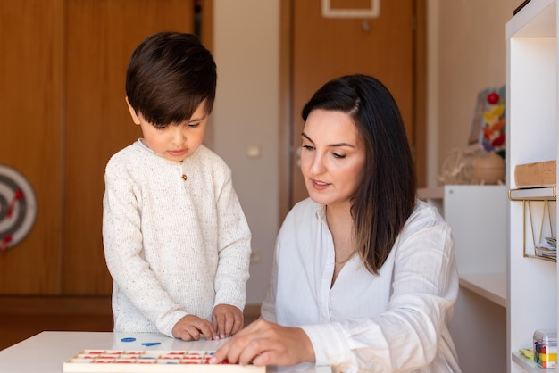 Lillte Kid lernt Schreiben und Lesen mit einem Alphabet und Mutter- oder Lehrerhilfe. Homeschooling. Lerngemeinschaft. Montessori-Schule