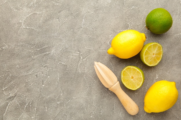 Lima fresca y limón con exprimidor de cítricos en gris. Ingrediente de preparación para cocinar con lima y limón.