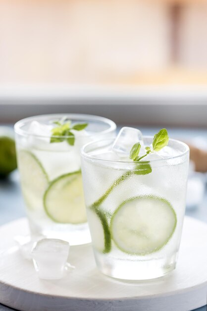 Lima limonada saludable con menta fresca y hielo en un vaso sobre fondo azul.