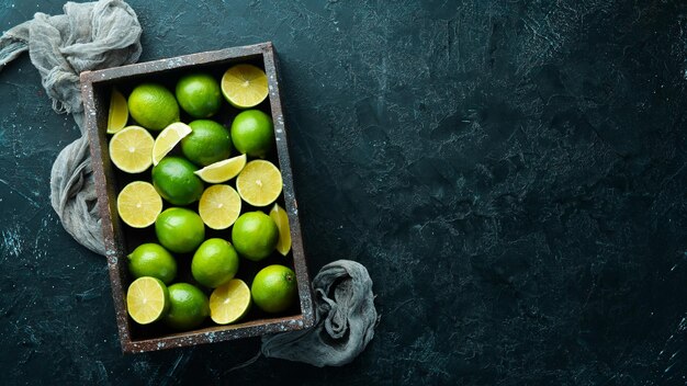 Lima verde en una caja de madera Cítricos Sobre un fondo de piedra negra Vista superior Espacio libre para su texto