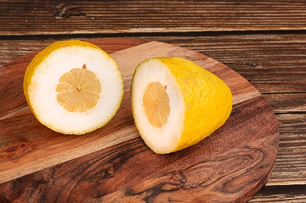 Limão amarelo grande para bombar uma tábua de corte em uma mesa de madeira