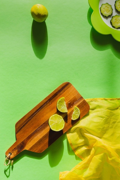 Limão cítrico sobre fundo verde em uma placa de madeira com sombras marcadas guardanapo amarelo e placa verde