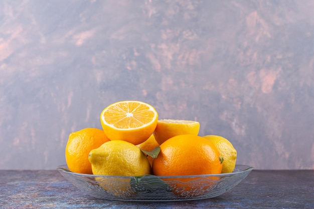 Limão com frutas fatiadas e inteiras colocadas em prato de vidro.