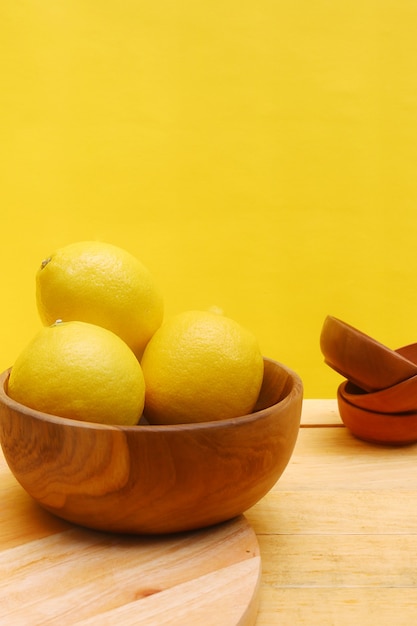 limão em uma tigela de madeira com fundo amarelo