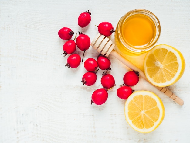 Limão fresco amarelo, jarro de mel e frutas vermelhas em uma mesa de madeira branca. Vista superior, close-up, isolada. Conceito de prevenção de resfriados