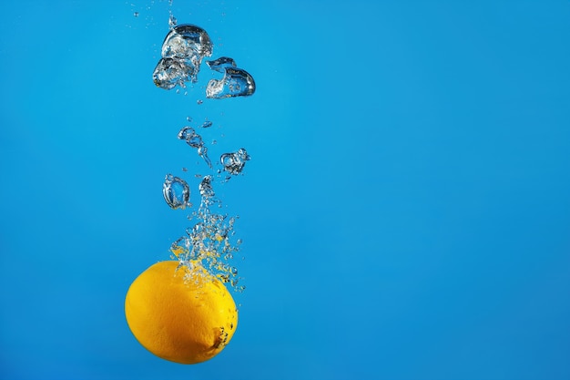 Limão fresco cai na água com um respingo