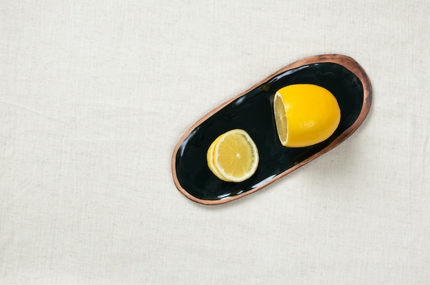 Limão fresco em pires na toalha de mesa de tecido, vista superior. Cerâmica artesanal