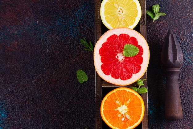 Limão laranja e toranja fatias coloridas com cítricos reamer em fundo escuro falt lay cena