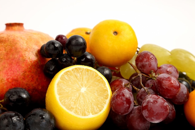 Foto limão, uvas e romã na superfície branca