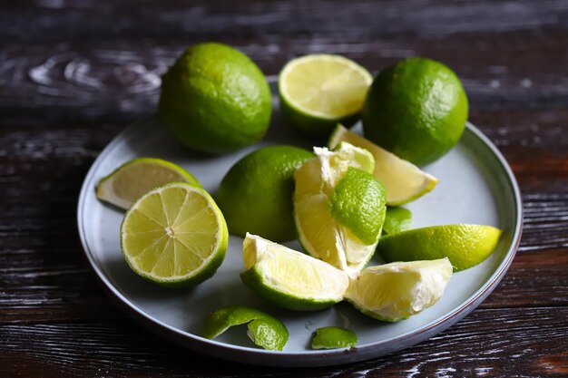 Limas y rodajas de limas sobre un fondo de madera oscura.