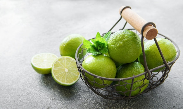 Limas verdes con hojas de menta fresca en cesta