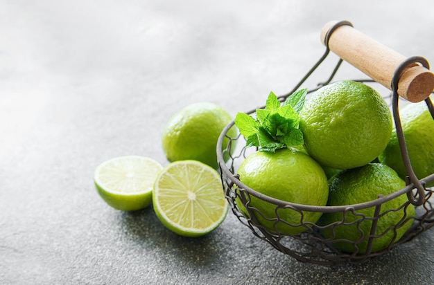 Limas verdes con hojas de menta fresca en cesta