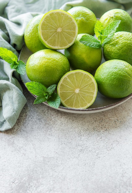 Limas verdes con hojas de menta fresca en un plato