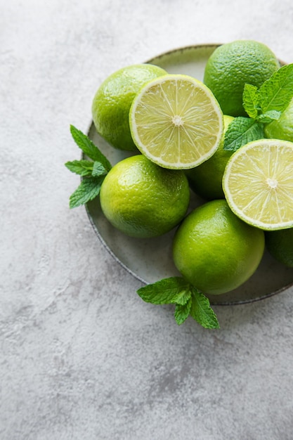 Limas verdes con hojas de menta fresca en un plato