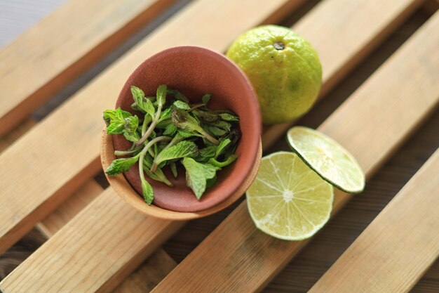 Limette und frische Minze in einer kleinen Keramikschale auf einem Holzgitter auf dem Tisch