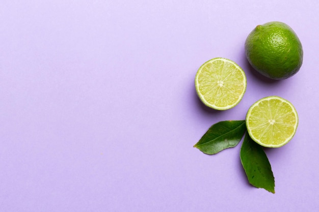 Limettenfrüchte mit grünem Blatt und in halbierte Scheiben geschnitten, isoliert auf weißem Hintergrund, Draufsicht, flache Lage mit Kopierraum