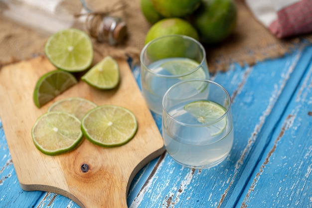 Limettensaft und Zitrone auf einem blauen Holztisch