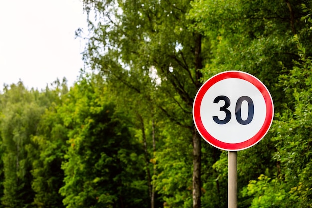 Foto limite de velocidade do sinal de estrada 30 quilômetros por hora no fundo da floresta verde com foco seletivo