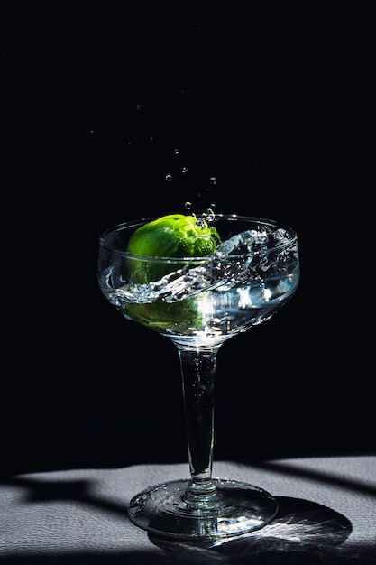 Limões caindo em um copo de cristal espirrando na água