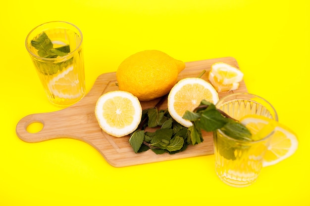Limões e água desintoxicante feitos deles em fundo amarelo