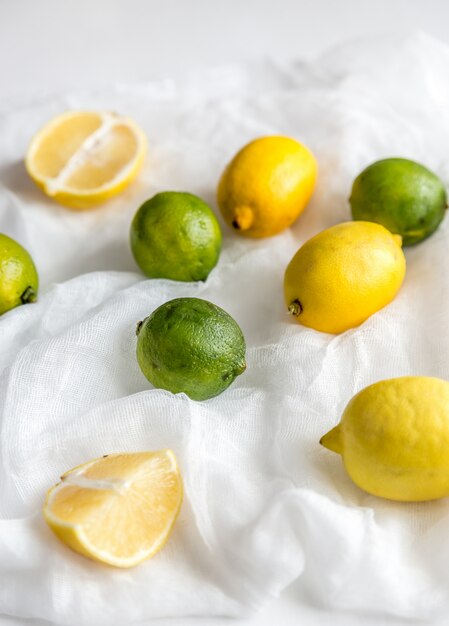 Foto limões e limas no fundo branco: frutas inteiras e cruz