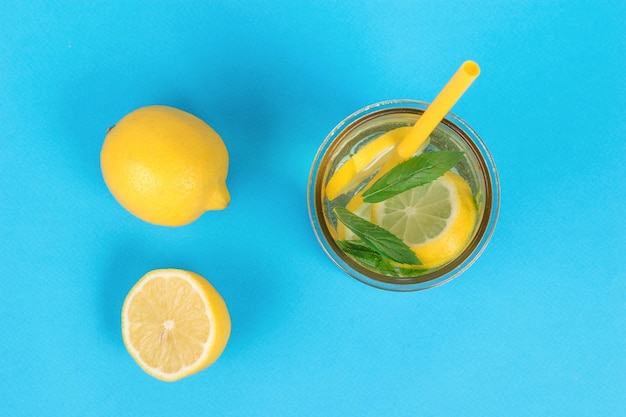 Limões frescos e um copo de limonada refrescante em um fundo azul