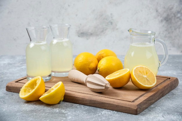 Limões, fundo cinza, suco de limão e fresco na tábua