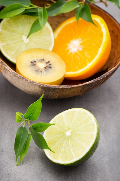 Limões mistos de frutas cítricas, laranja, kiwi, lima em uma mesa cinza.