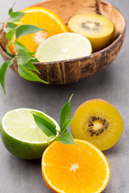 Limões mistos de frutas cítricas, laranja, kiwi, limas sobre um fundo cinza.