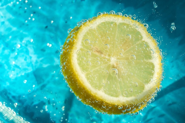 limón amarillo fresco en agua azul clara con burbujas